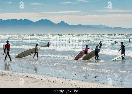 Surfer und Badegäste am Strand von Muizenberg in Kapstadt, Südafrika. Stockfoto