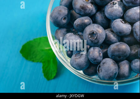 Frisch Blaubeeren in Houten abgeholt. Saftig und frischen Blaubeeren mit grünen Blättern auf rustikalen Tisch. Heidelbeere auf Holz- Hintergrund. Blueberry Antioxidans. Konzept für gesundes Essen und Ernährung Stockfoto