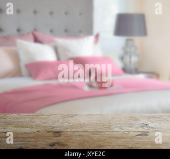 Holz- Tischplatte mit Unschärfe der roten Bett und Kissen, modernes Schlafzimmer als Hintergrund Stockfoto