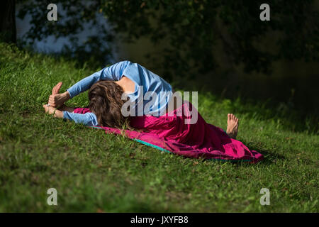 Frau praktiziert Yoga Asana im Park am Morgen. Stockfoto