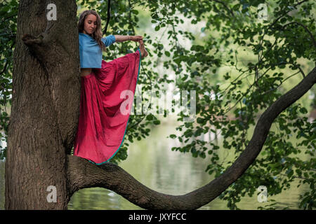 Kaukasische Frau, im Yoga balance Utthita Hasta Padangusthasana darstellen. Sie trank von Baum Stockfoto