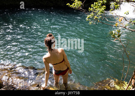 Kaukasische Frau waten in Pool in der Nähe von Wasserfall Stockfoto