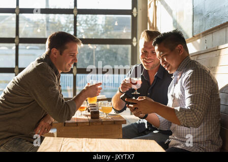 Freunde SMS auf Handy in Brew Pub Stockfoto