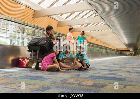 Kinder warten im Flughafen mit der Familie und mit digitalen Tablet Stockfoto
