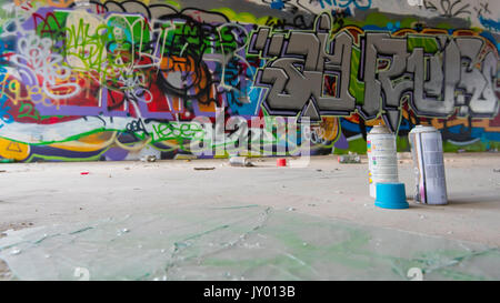 Sprühen Sie in einem verlassenen Geschäftsgebäude in Sydney, Australien, bemalte und mit Graffiti gekennzeichnete Wände und Aerosoldosen Stockfoto