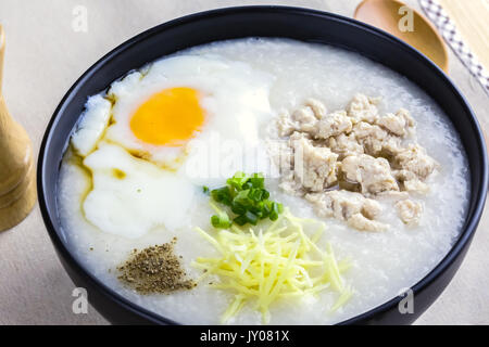 Reisbrei ist Richtfest mit Ingwer, Frühlingszwiebeln, Paprika, Huhn, und Onsen Ei, Frühstück auf Holztisch, Löffel, pepper Grinder. Frühstück Stockfoto