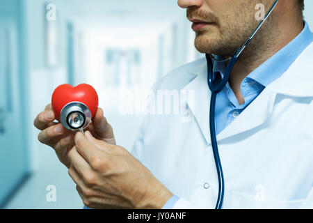 Kardiologe Kontrolle rotes Herz mit Stethoskop. Kardiologie Konzept Stockfoto
