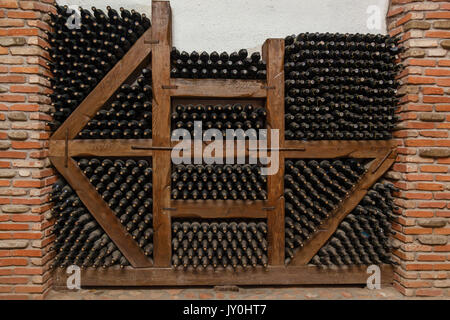 Winy Flaschen liegen in Vitrinen aus dicken, alten Weinkeller mit Flaschen und Fässer Stockfoto