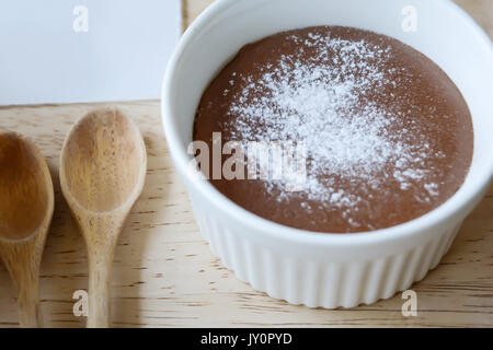 Schokolade Lava in weiße Tasse mit Löffel Pulver und Holz auf Holz Tisch. Dessert auf Holz prop. Coffee shop Dessert. Stockfoto