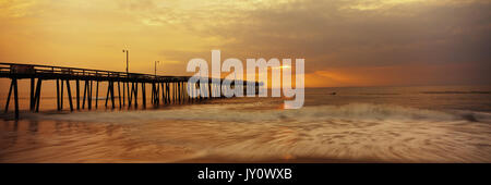 Ozean Wellen unter Pier bei Sonnenuntergang Stockfoto