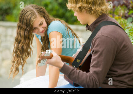 Kaukasische Junge spielt Gitarre für Mädchen Stockfoto