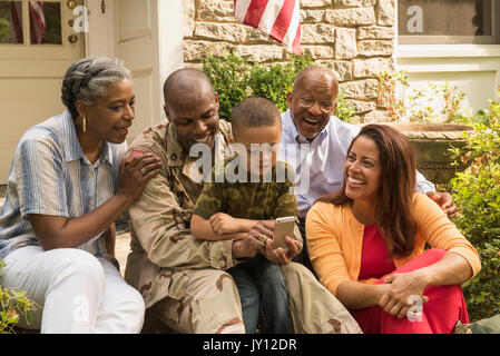 Soldat und multi-Generation, Familie, die auf dem Mobiltelefon Stockfoto
