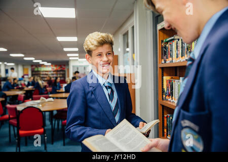 Zwei Teenager Studenten zusammen, die in der Schulbibliothek, Reden und Bücher zu lesen. Stockfoto