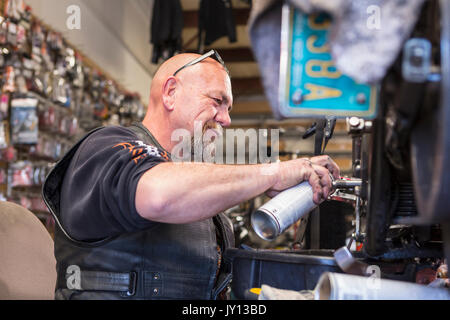 Kaukasische Mann spritzen Schmiermittel auf Motorrad Stockfoto