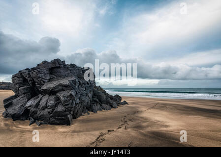 Fußspuren am Strand in der Nähe von Rock Formation Stockfoto