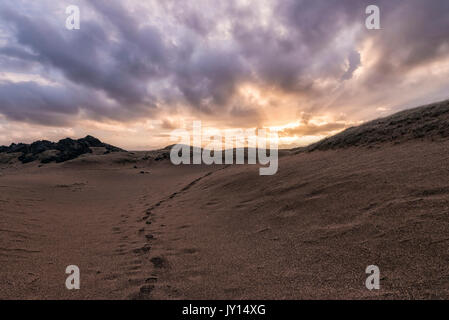 Fußspuren im Sand bei Sonnenuntergang Stockfoto