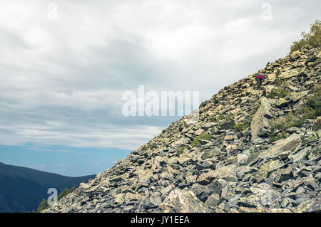 Ein Tourist macht seinen Weg durch den Stein placers Mann Aufstieg auf den Berg Hügel