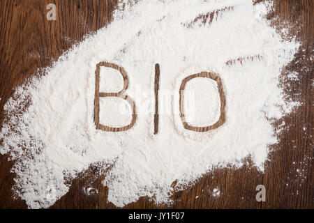 Hohe Betrachtungswinkel von Bio Text auf weißem Mehl an den hölzernen Schreibtisch geschrieben Stockfoto