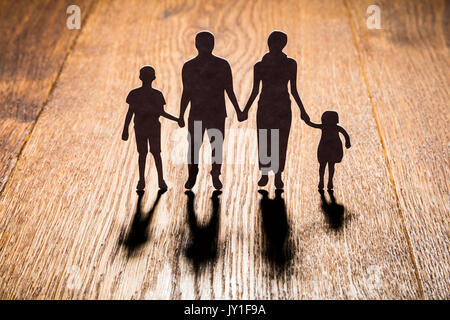 Silhouette von Familie Papercut auf hölzernen Schreibtisch Stockfoto