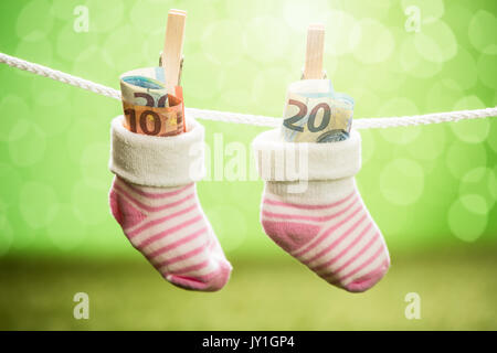 Paar Baby Socken mit Dollar hängen am Seil mit hölzernen Clip Stockfoto