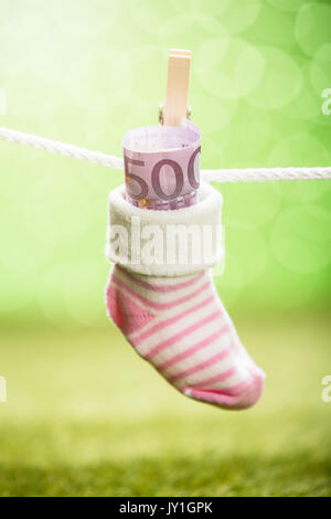 Baby Socken mit Dollar hängen am Seil mit hölzernen Clip Stockfoto