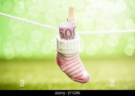 Baby Socken mit Dollar hängen am Seil mit hölzernen Clip Stockfoto