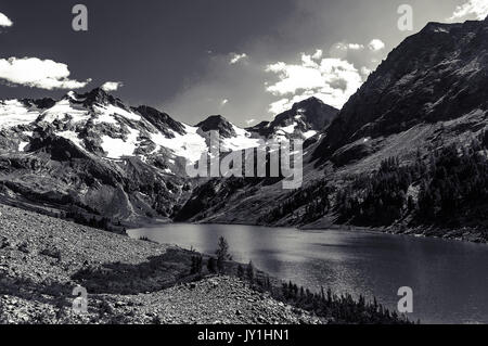 Schöne schwarze und weiße Landschaft und hohe schneebedeckte Berge und See zwischen den Gebirgszügen Stockfoto