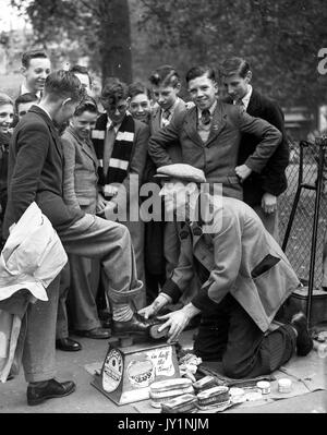 Deaktiviert Schuhputzmaschine/-Mann mit nur einem Bein polieren school Jungen Schuhe auf in London 1954 Schuhputzmaschine/-mann. Stockfoto