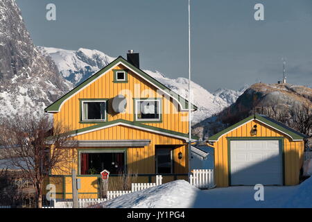 Gelbe Cottages - Snowy Reine Stadt. Der festhaeltinden-akkarviktinden Moskenesoya und Sundmannen von Flakstadoya mounts zusammen mit Olenilsoya Insel hinterg Stockfoto