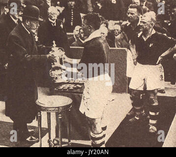 1934 - König George V. von England hier die Gewinner Schale an der AFC-Finale in Wembley, London, Kapitän, Sam Cowan von Manchester United, das schlug Portsmouth 2-1 zu Team. Stockfoto