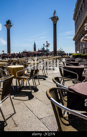 Street Café für Touristen in San Marco Platz mit Blick von San Marco und San Todaro Spalten in Venedig, Italien warten Stockfoto