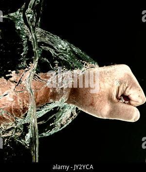 'Lochen durch Wasser" - in der Nähe von Faust eines Mannes Stanzen durch Wasser horizontal, Anzeige von Bewegung und Kraft gegen Schwarz. Stockfoto