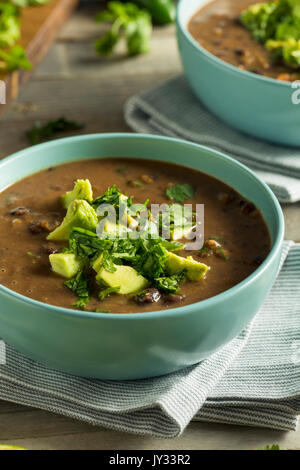 Frische hausgemachte schwarze Bohnensuppe mit Avocado und Koriander Stockfoto