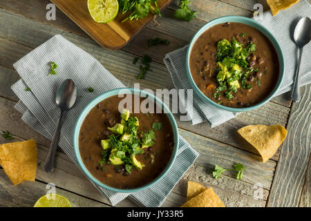 Frische hausgemachte schwarze Bohnensuppe mit Avocado und Koriander Stockfoto