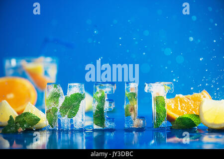 Ice Cube Schriftzug mit gefrorenen Minze, Zitronenscheiben und Orangen auf einem blauen Hintergrund mit Wasser spritzt. Text sagt Schmelzen. Stockfoto