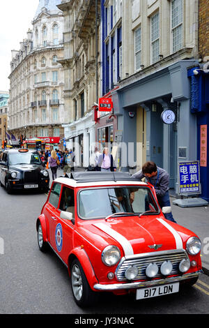 Eine klassische Mini Auto mit einer von Londons berühmten schwarzen Taxis hinter sich, in der Wardour Street, Soho, London in der Nähe von Chinatown. Stockfoto