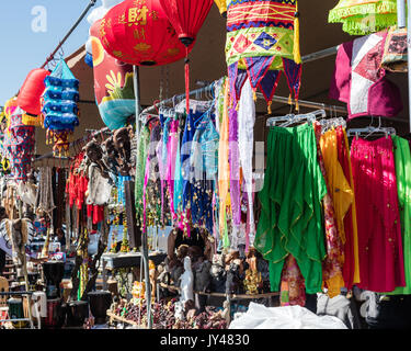 Flohmarkt Anbieter verkaufen viele bunte Asiatische Kleidungsstücke zusammen mit Statuen, hängende Dekorationen und sonstige Schmuckstücke inspirieren. Stockfoto