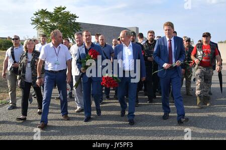 Sewastopol, Russland. 18 Aug, 2017. Der russische Präsident Wladimir Putin, Mitte, Ministerpräsident Dimitri Medwedew, Links, und Gouverneur von Sewastopol Dmitry Ovsyannikov, rechts, während einer Zeremonie zu Ehren der Erinnerung an die Sewastopol Verteidiger während des Zweiten Weltkrieges am Maxim Gorki Festung 35th Küsten Batterie Memorial am 18. August in Sewastopol, Krim, Russland 2017. Credit: Planetpix/Alamy leben Nachrichten Stockfoto