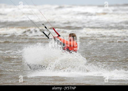 Southport, Merseyside, 19. August 2017. UK Wetter. Ein wirklich windig und viel cooler Tag mit einigen schweren vereinzelte Schauer dieser Kite boarder nicht davon abhalten, die Brandung an der Flut in Southport, Merseyside. Credit: cernan Elias/Alamy leben Nachrichten Stockfoto