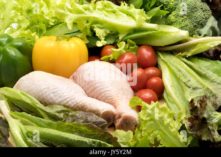 Frisches rohes Huhn und verschiedene Arten von Gemüse auf einem Holztisch Stockfoto