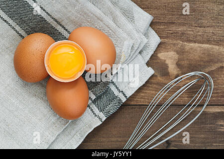 Draufsicht auf frische Eier und Schneebesen zum Schlagen. Kochen Konzept. Stockfoto