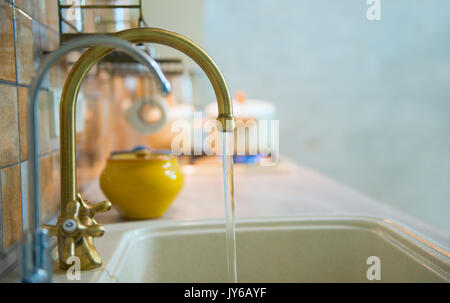 Moderne, trendige, bronze Wasserhahn in einem neuen, modernen Küche. Aus dem Wasserhahn fließt Leitungswasser Stockfoto