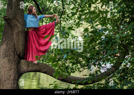 Kaukasische Frau, im Yoga balance Utthita Hasta Padangusthasana darstellen. Sie trank von Baum Stockfoto