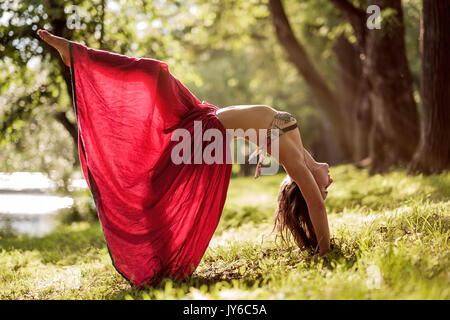 Passen junge schöne Frau das Tragen der roten Rock, im Freien arbeiten im Park im Sommer Tag, Brücke Darstellen von Yoga Stockfoto