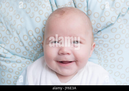 Porträt einer niedlichen Baby Junge sitzt und lächelt. Adorable sieben Monate alten Kind glücklich lachend. Stockfoto