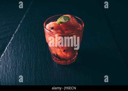 Wassermelone Cocktail in ein rotes Glas auf einem Schwarzen Tisch closeup Stockfoto