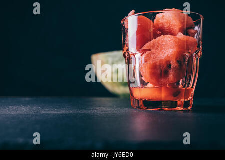 Glas mit in Scheiben geschnittenen Wassermelone auf einem Schwarzen Tisch close-up Stockfoto