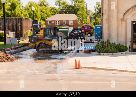 Zwei Arbeiter bedienen Erdbewegungsmaschinen tun Bau Reparatur in einer Gasse in Norman, Oklahoma, USA. Stockfoto