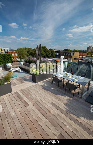 Luxuriöse Dachterrasse in London mit Schnittholz Terassendielen, zeitgenössische Pflanzmaschinen mit üppiger Bepflanzung und moderne Gartenmöbel Stockfoto