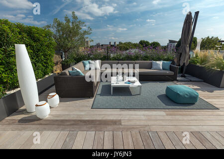 Luxuriöse Dachterrasse in London mit Schnittholz Terassendielen, zeitgenössische Pflanzmaschinen mit üppiger Bepflanzung und moderne Gartenmöbel Stockfoto